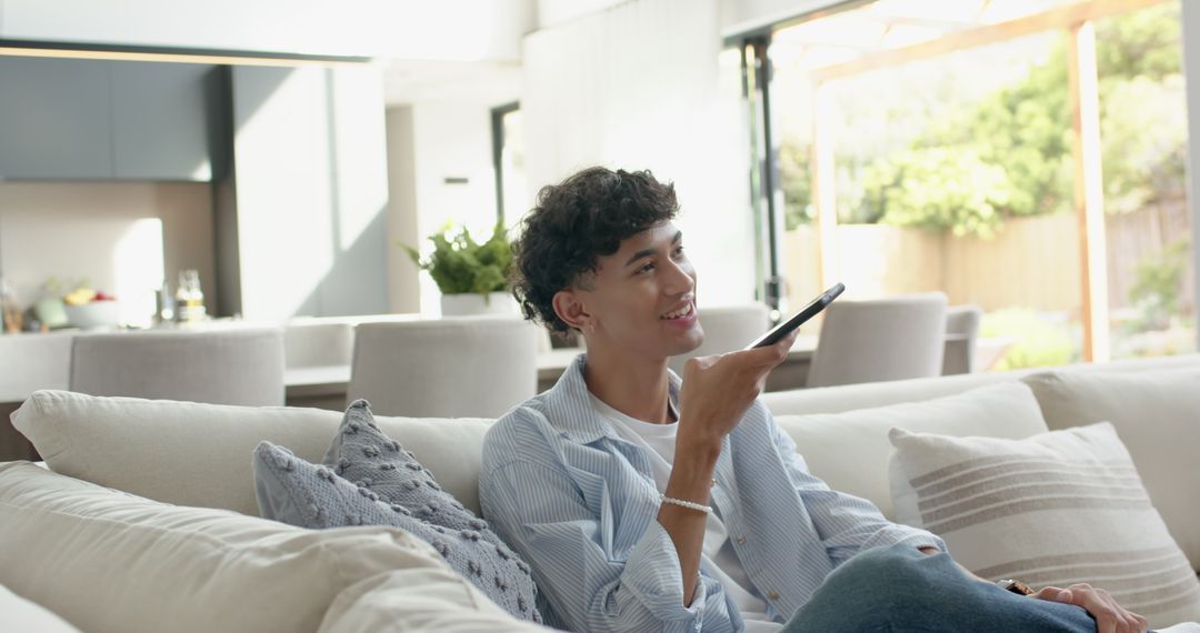 Man Relaxing on Sofa Communicating Via Smartphone