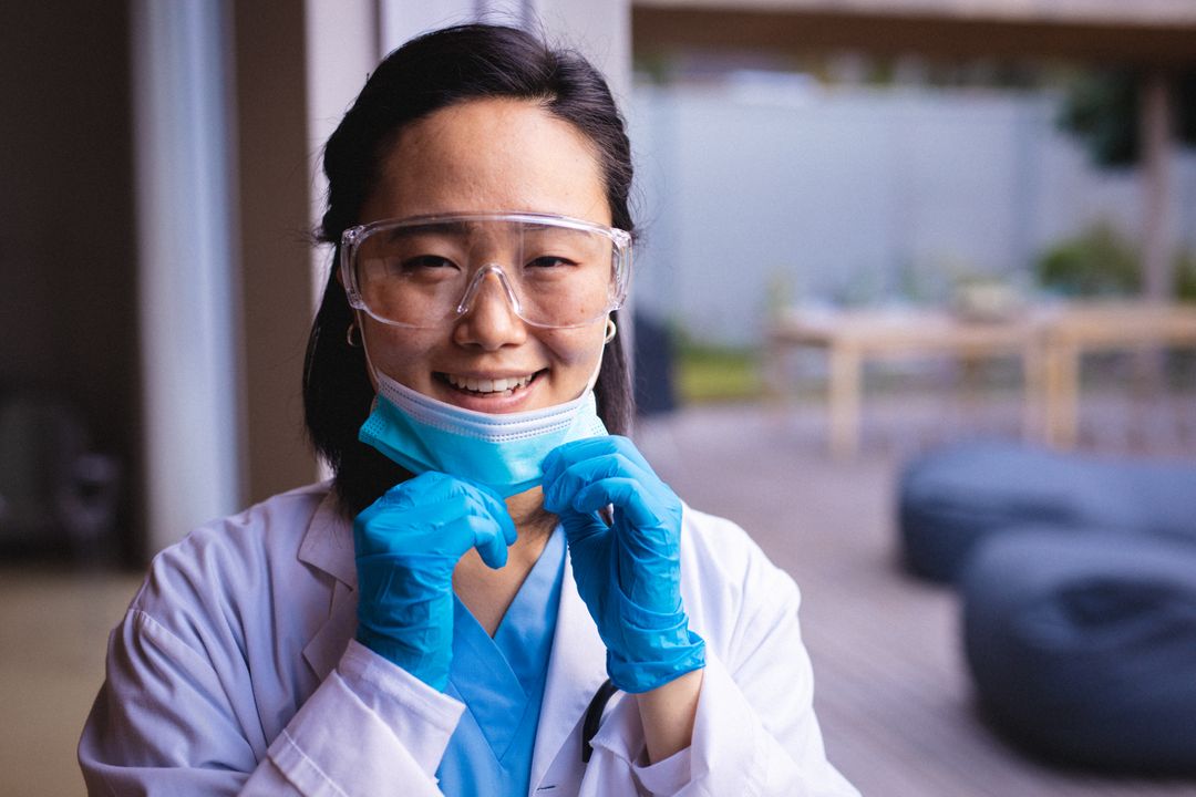 Portrait of smiling asian doctor wearing protective glasses and face mask looking at camera - Free Images, Stock Photos and Pictures on Pikwizard.com