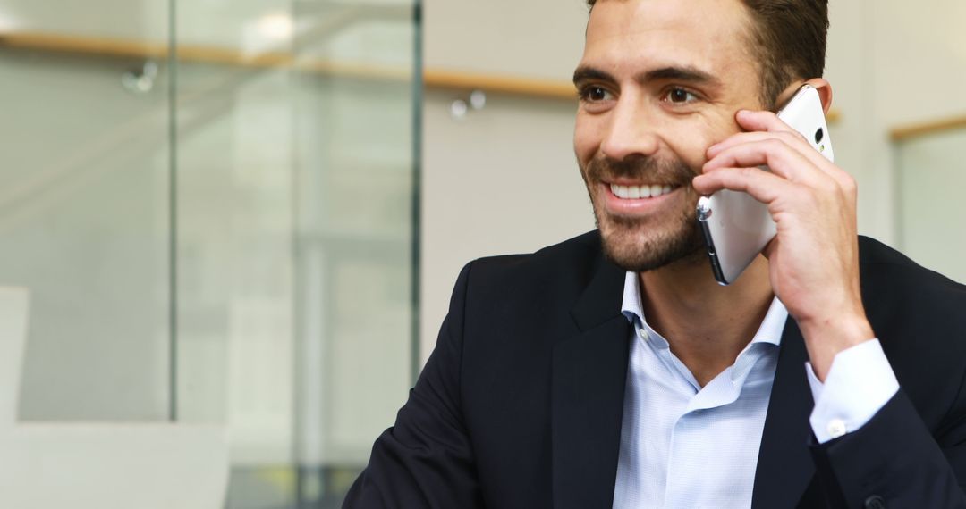 Young Businessman Talking on Smartphone in Modern Office - Free Images, Stock Photos and Pictures on Pikwizard.com