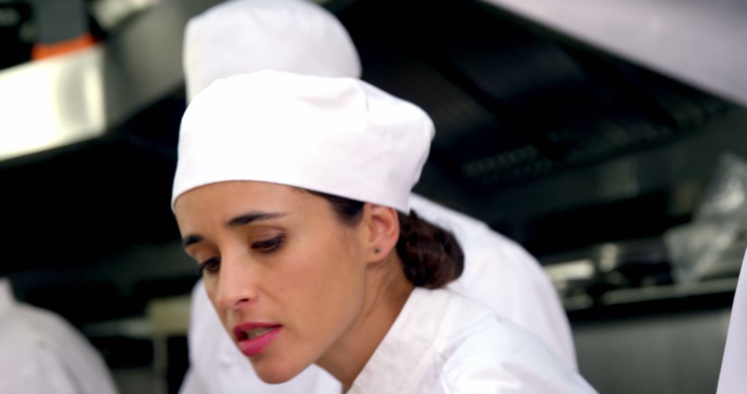 Focused Female Chef Wearing White Uniform in Professional Kitchen