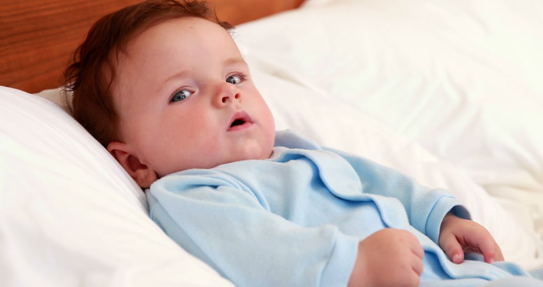 Adorable Baby Relaxing on Bed in Soft Blue Pajamas - Free Images, Stock Photos and Pictures on Pikwizard.com