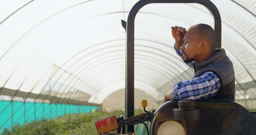 Agricultural Worker on Tractor Inspecting Greenhouse Fields - Free Images, Stock Photos and Pictures on Pikwizard.com