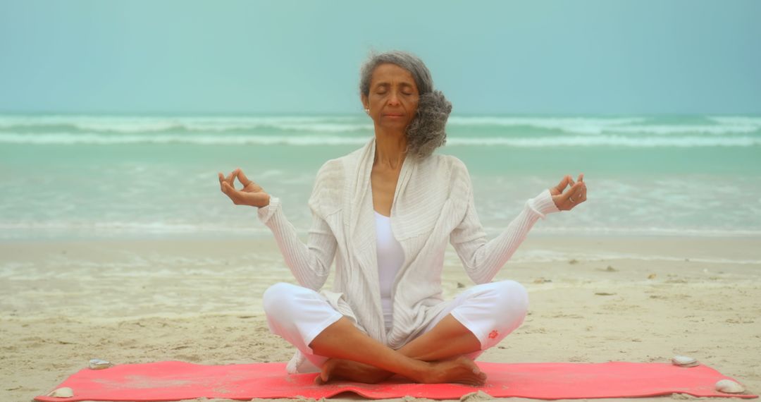 Serene Senior Woman Meditating on Beach in Lotus Pose