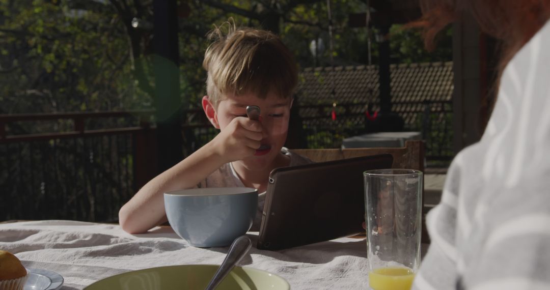 Young Boy Eating Breakfast Outdoors with Tablet - Free Images, Stock Photos and Pictures on Pikwizard.com