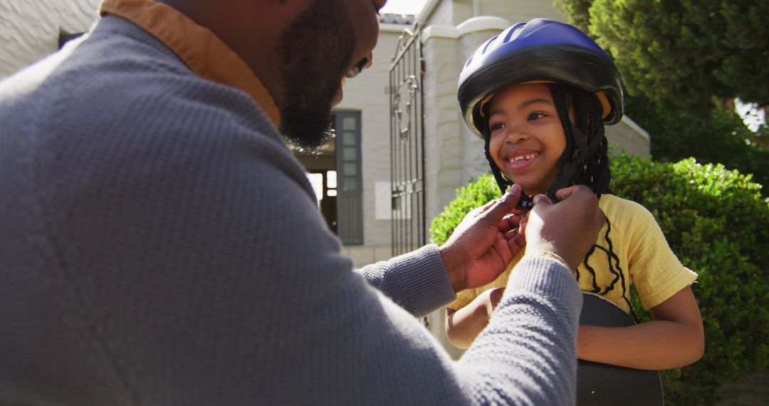 Father Helping Daughter With Helmet Smiling Outdoors