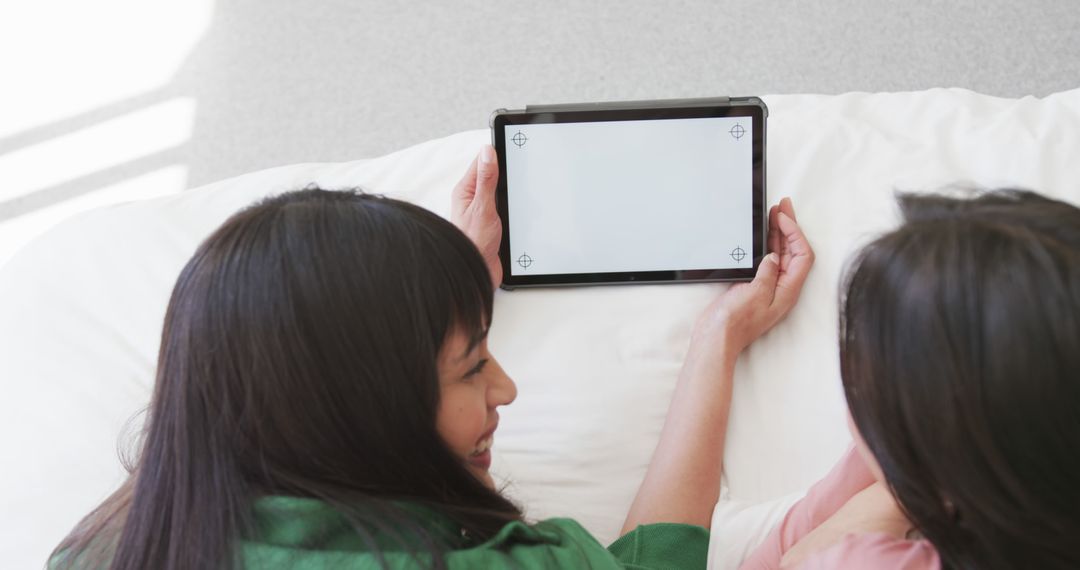 Two Women Relaxing on Bed Watching Tablet Together - Free Images, Stock Photos and Pictures on Pikwizard.com