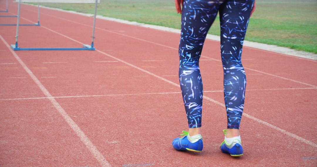 A person stands on a track field ready to run, showcasing athletic footwear and sportswear - Free Images, Stock Photos and Pictures on Pikwizard.com