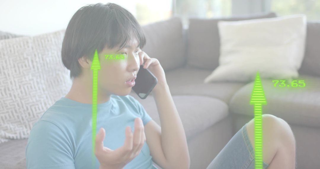 Young Asian man talking on phone at home showing green augmented reality data overlays