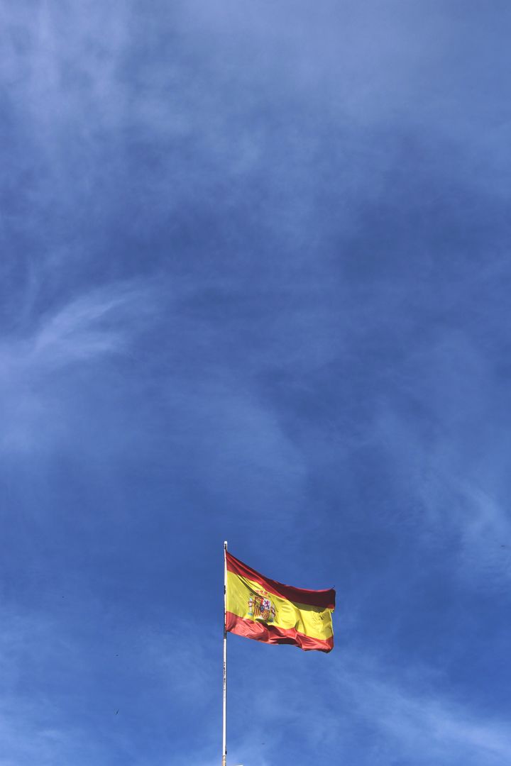 Spanish Flag Waving Against Clear Blue Sky - Free Images, Stock Photos and Pictures on Pikwizard.com