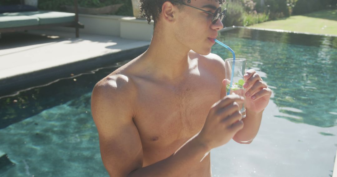 Young Man Drinking Refreshing Beverage by Poolside on Sunny Day - Free Images, Stock Photos and Pictures on Pikwizard.com