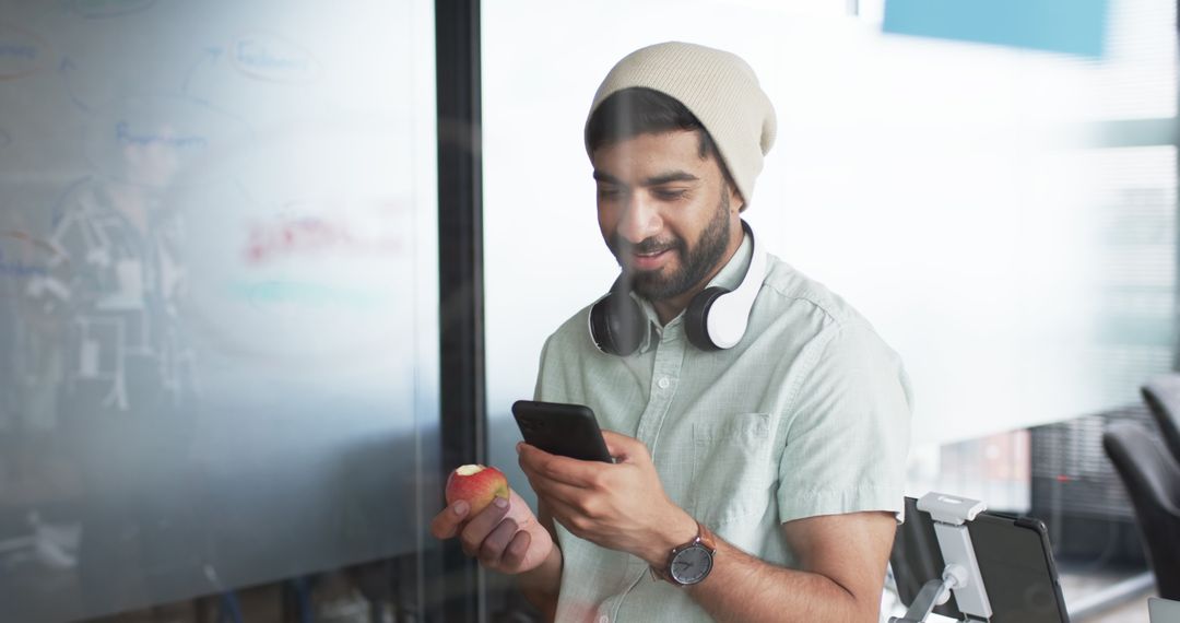 Young Professional Asian Male Checking Smartphone Relaxed in Office Casual