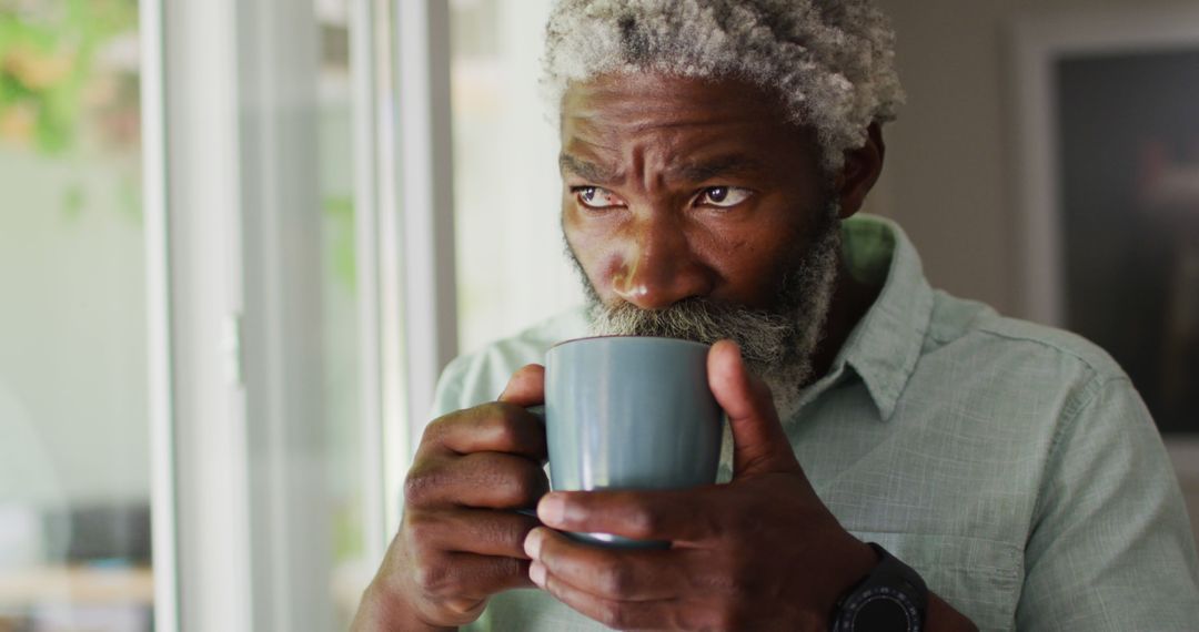 An elderly African American man enjoys coffee and smiles while in quarantine at home. - Free Images, Stock Photos and Pictures on Pikwizard.com
