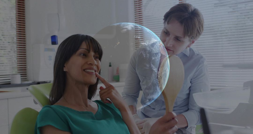 Smiling dental patient receiving checkup while dentist holding mirror and advising