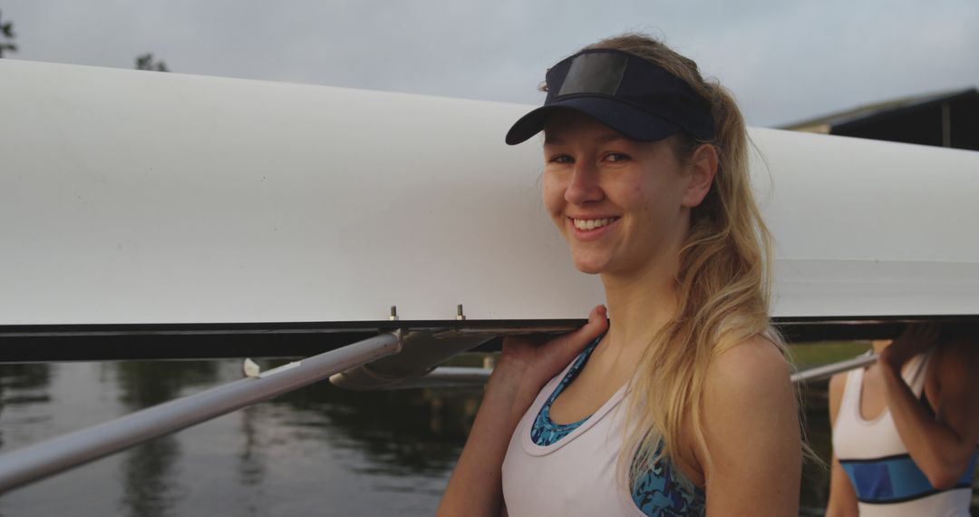 Smiling Female Rower Carrying Boat by Riverside - Free Images, Stock Photos and Pictures on Pikwizard.com