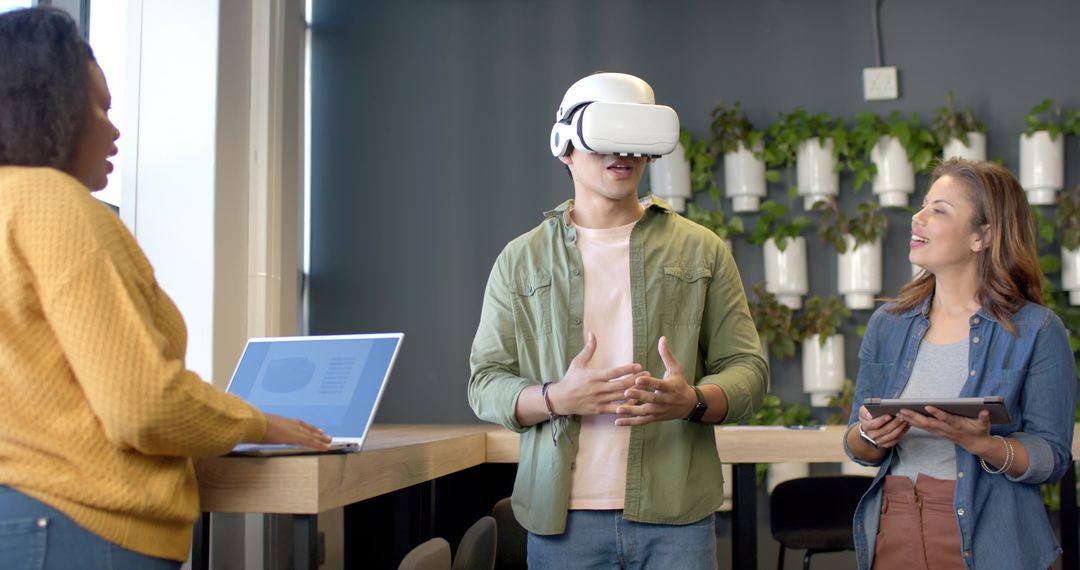 Team testing VR headset while collaborating with laptop and tablet in green workspace