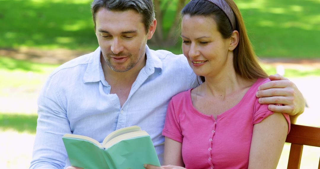 Couple Joyfully Reading Book Together on Sunny Park Bench