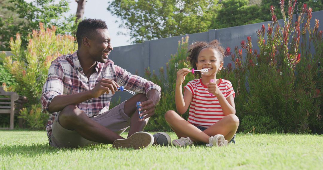 Father and Daughter Blowing Bubbles in Sunny Backyard - Free Images, Stock Photos and Pictures on Pikwizard.com