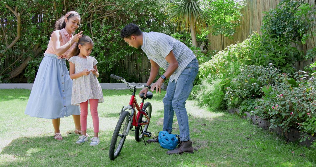Father Adjusting Daughter's Bicycle in Sunny Backyard