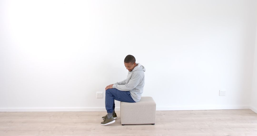 Man Performing Exercise at Home on Ottoman in Minimalist Space