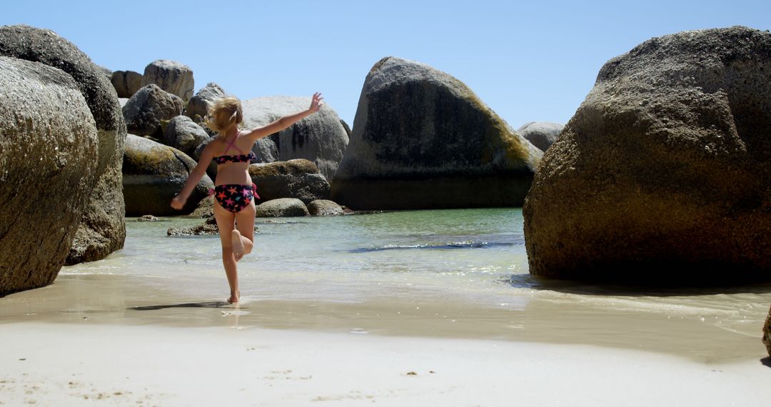 Girl Running on Beach Between Rock Formations on Sunny Day - Free Images, Stock Photos and Pictures on Pikwizard.com