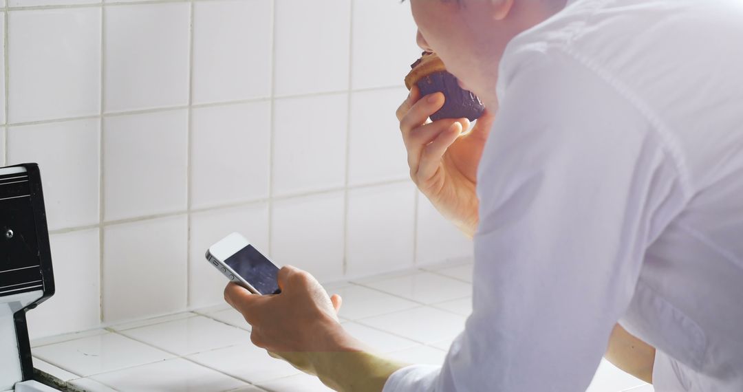 Person Eating Breakfast and Using Smartphone in Kitchen - Free Images, Stock Photos and Pictures on Pikwizard.com