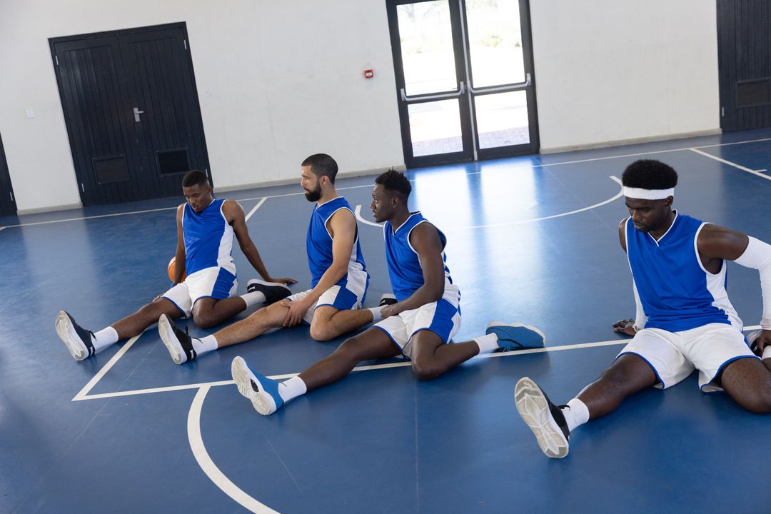 Multiracial Basketball Team Stretching on Indoor Court