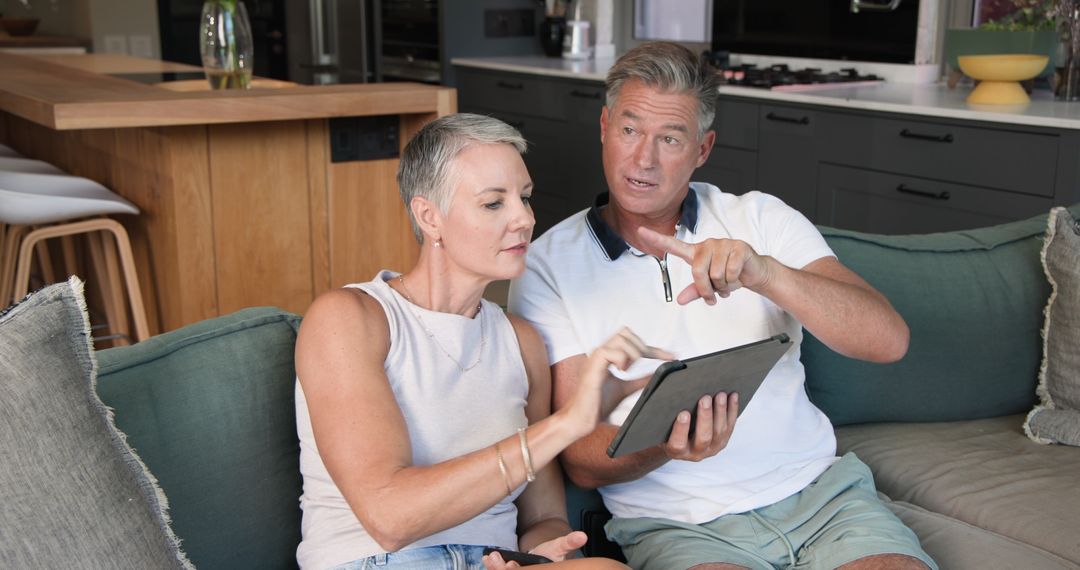 Senior Couple Relaxing on Sofa Using Tablet in Modern Home