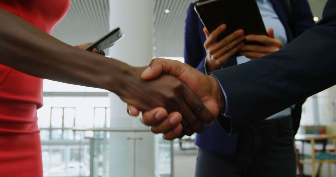 Business Professionals Shaking Hands in Modern Office Building - Free Images, Stock Photos and Pictures on Pikwizard.com