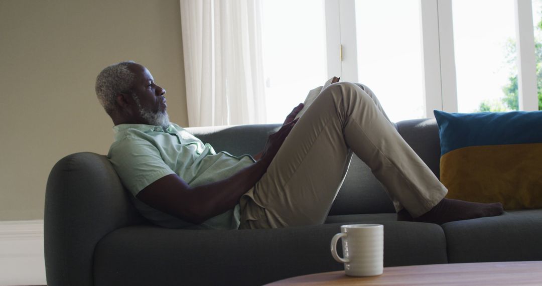 Elderly African American Man Relaxing on Couch Reading Book - Free Images, Stock Photos and Pictures on Pikwizard.com