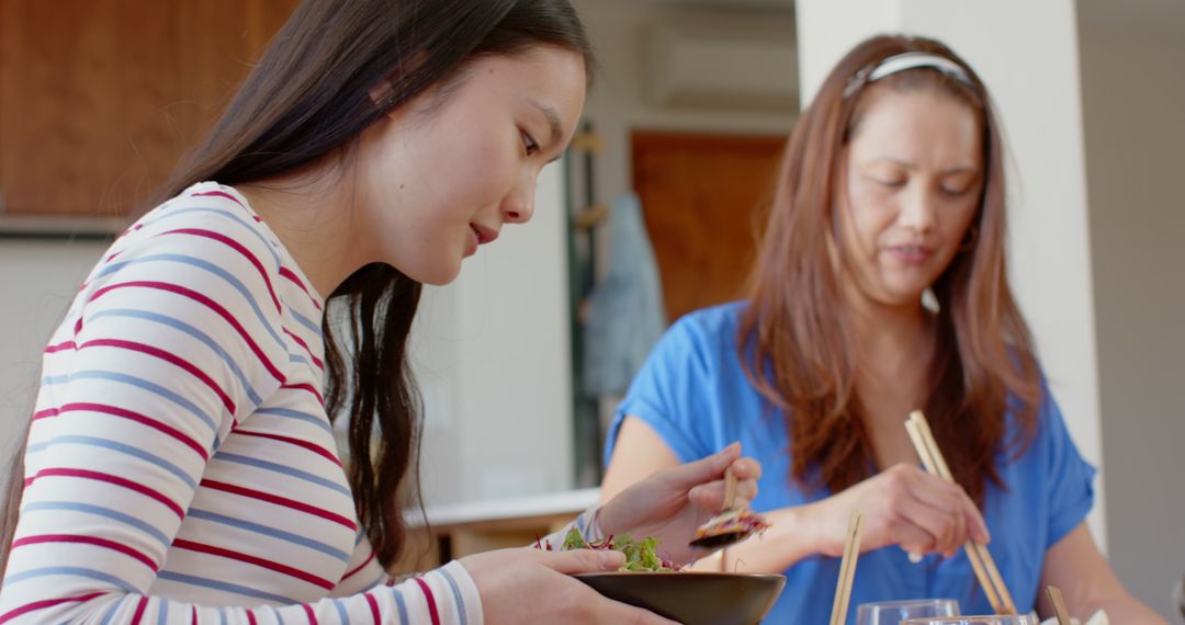 Mother and Daughter Enjoying Family Dinner with Chopsticks at Home