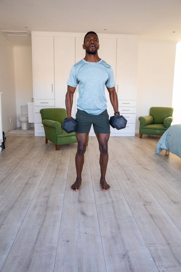 Man Exercising with Dumbbells in Bedroom for Home Workout Routine