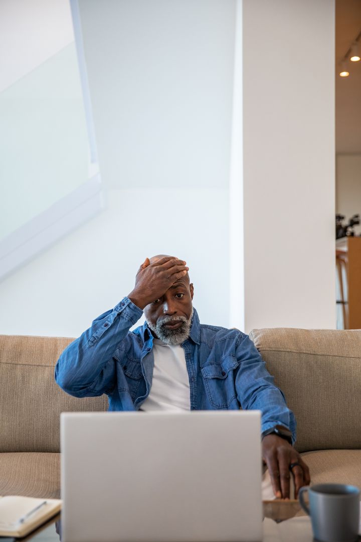Senior Man in Thought While Viewing Laptop in Cozy Home