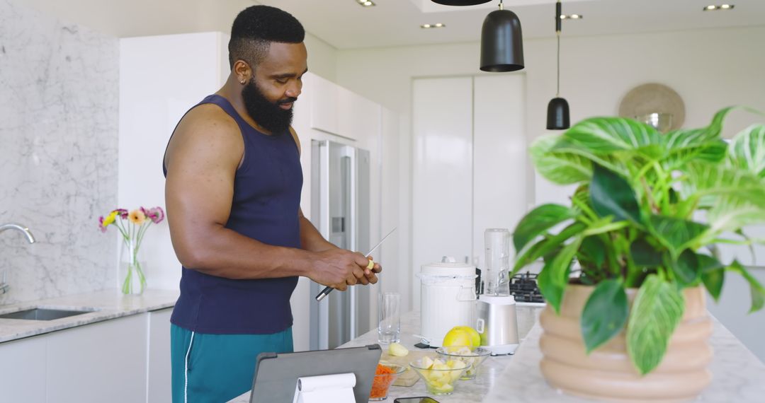 Man Slicing Pineapple in Modern Kitchen with Green Foliage