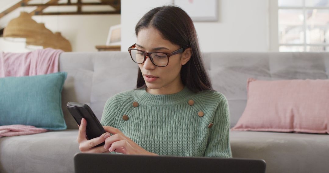 Biracial woman using smartphone and working in living room - Free Images, Stock Photos and Pictures on Pikwizard.com