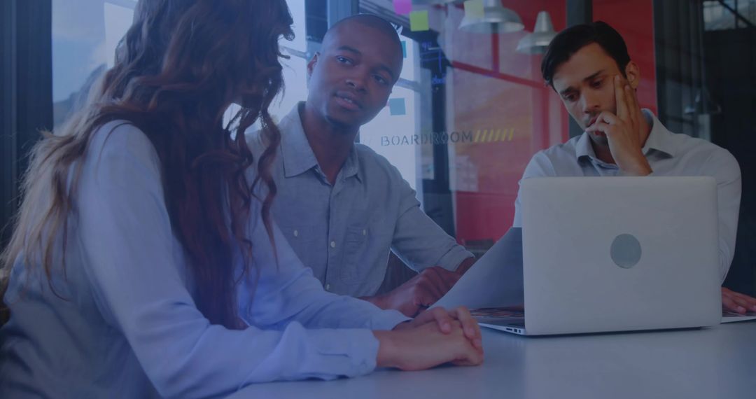 Discussing Strategy in Glass Boardroom, Team Collaborating Around Laptop and Documents