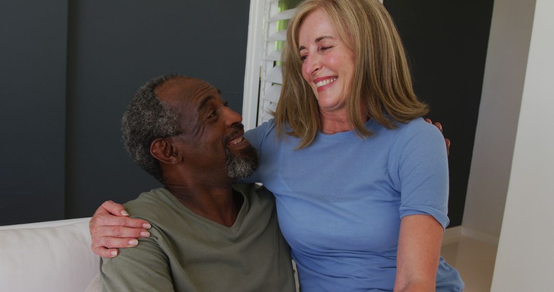 Portrait of biracial senior couple smiling while sitting on the couch at home - Free Images, Stock Photos and Pictures on Pikwizard.com