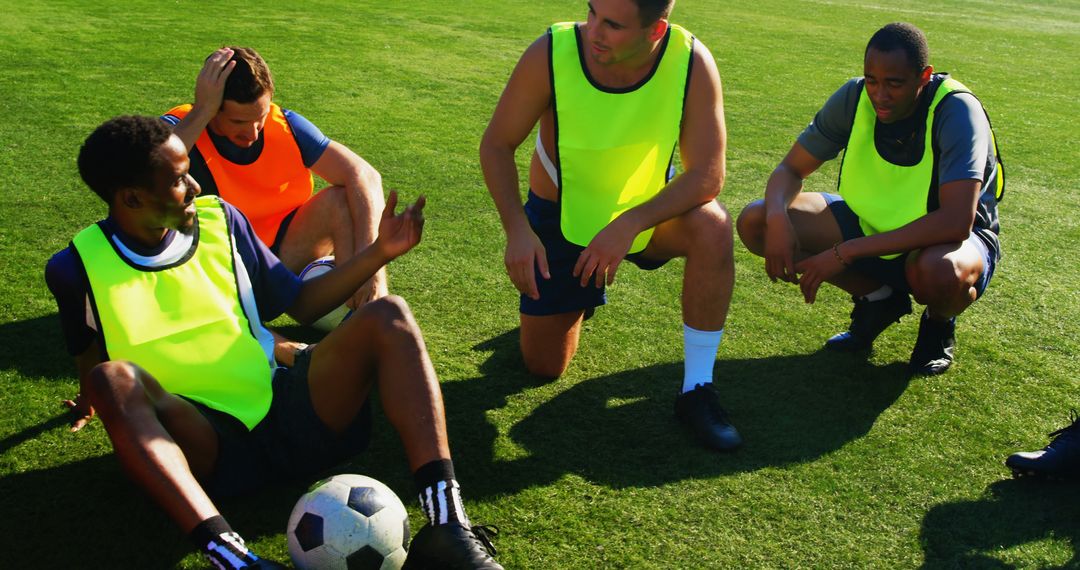 Four Male Soccer Players Resting on Field and Discussing Game Strategy - Free Images, Stock Photos and Pictures on Pikwizard.com