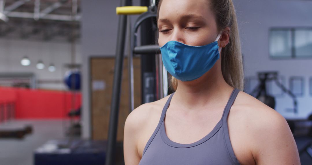 Young woman meditating with face mask in gym during COVID-19 - Free Images, Stock Photos and Pictures on Pikwizard.com