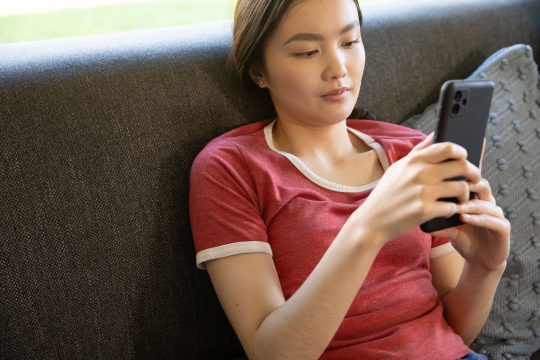 Young Woman Relaxing on Sofa Using Smartphone