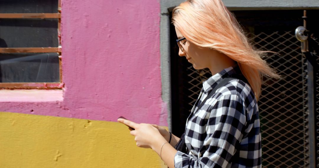 Woman with Pink Hair Using Smartphone Near Colorful Wall - Free Images, Stock Photos and Pictures on Pikwizard.com