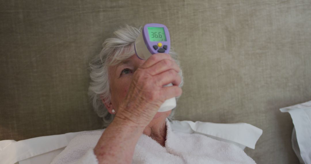 Elderly Woman Checking Temperature in Bed Using Digital Thermometer - Free Images, Stock Photos and Pictures on Pikwizard.com