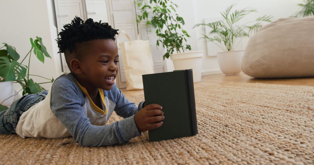 Smiling Young Boy Reading Book on Floor in Cozy Room - Free Images, Stock Photos and Pictures on Pikwizard.com