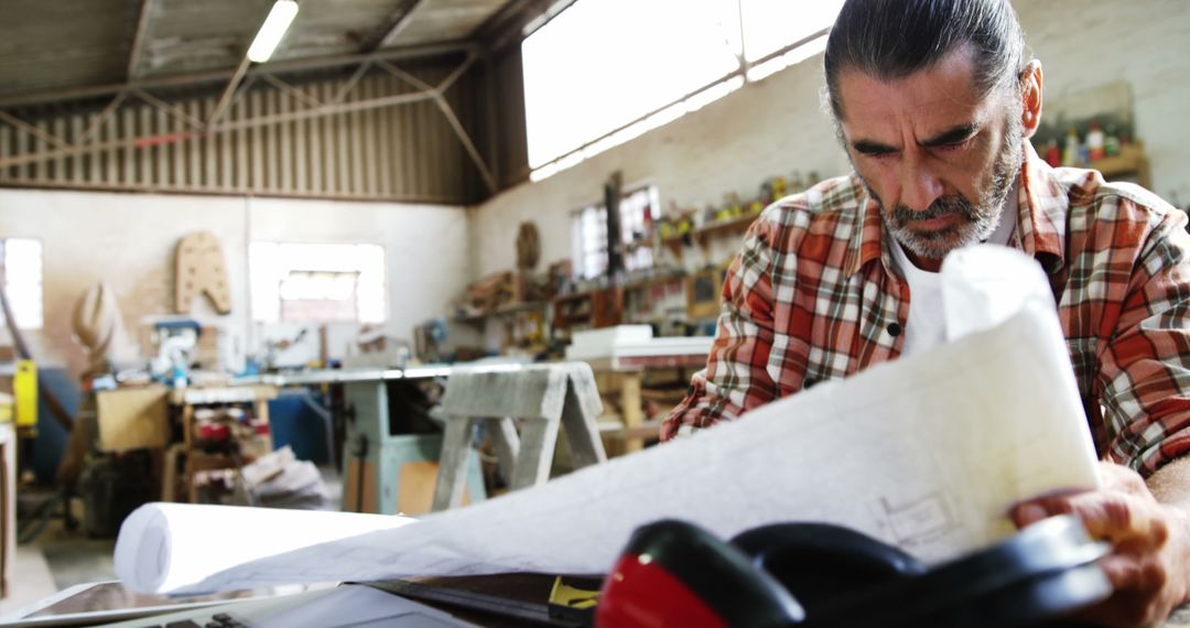 Carpenter Reviewing Blueprint in Wood Workshop