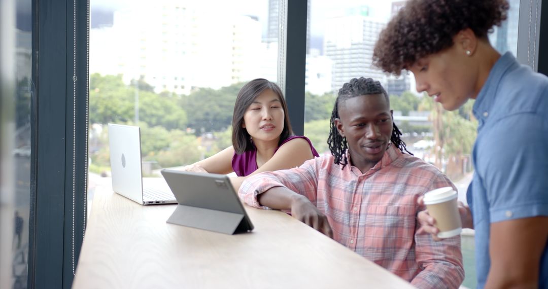Diverse Team Discussing Insights Over laptops in Modern Office