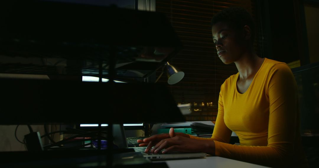 Focused Woman Working Late on Laptop in Dimly Lit Office - Free Images, Stock Photos and Pictures on Pikwizard.com