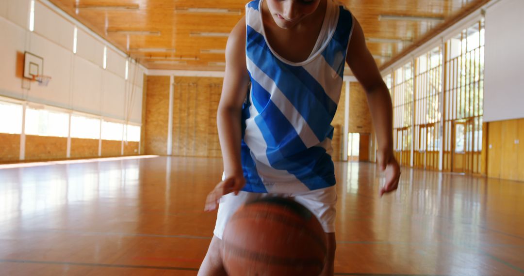 Female Basketball Player Dribbling Ball in Gym with Sunlight Through Windows - Free Images, Stock Photos and Pictures on Pikwizard.com