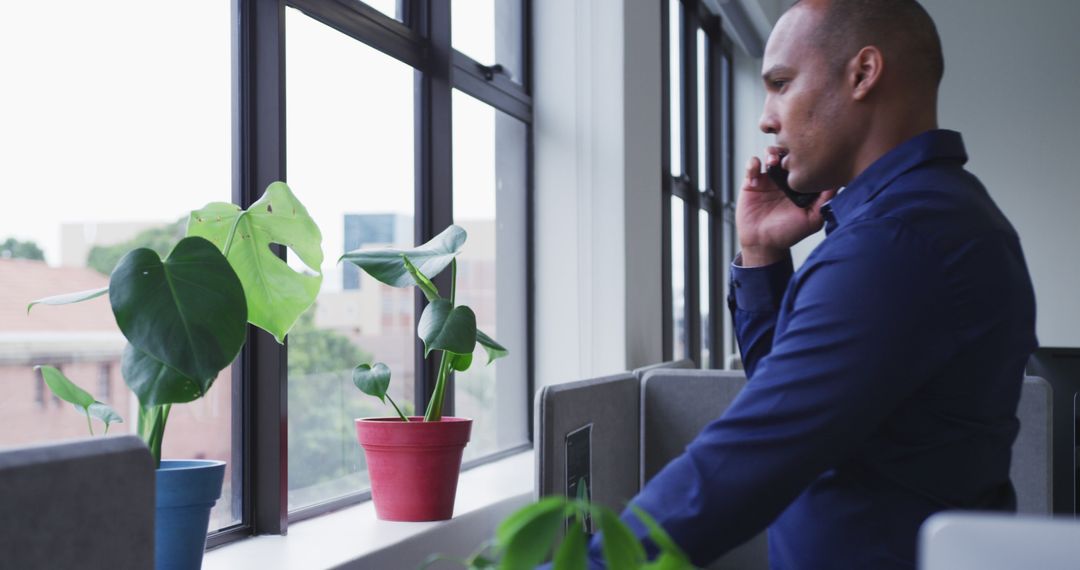 Businessman Making Phone Call in Modern Office Near Window - Free Images, Stock Photos and Pictures on Pikwizard.com