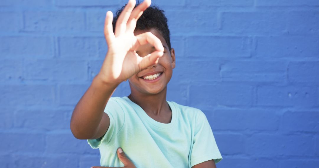 Smiling Boy Gesturing Playfully Against Blue Backdrop
