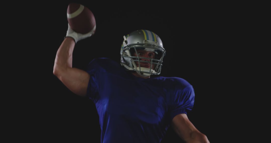 American Football Player Preparing to Throw Ball Against Black Background - Free Images, Stock Photos and Pictures on Pikwizard.com