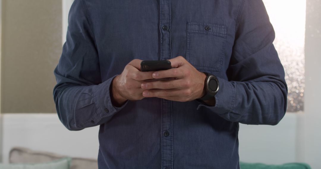 Man Wearing Blue Shirt Using Smartphone Indoors - Free Images, Stock Photos and Pictures on Pikwizard.com